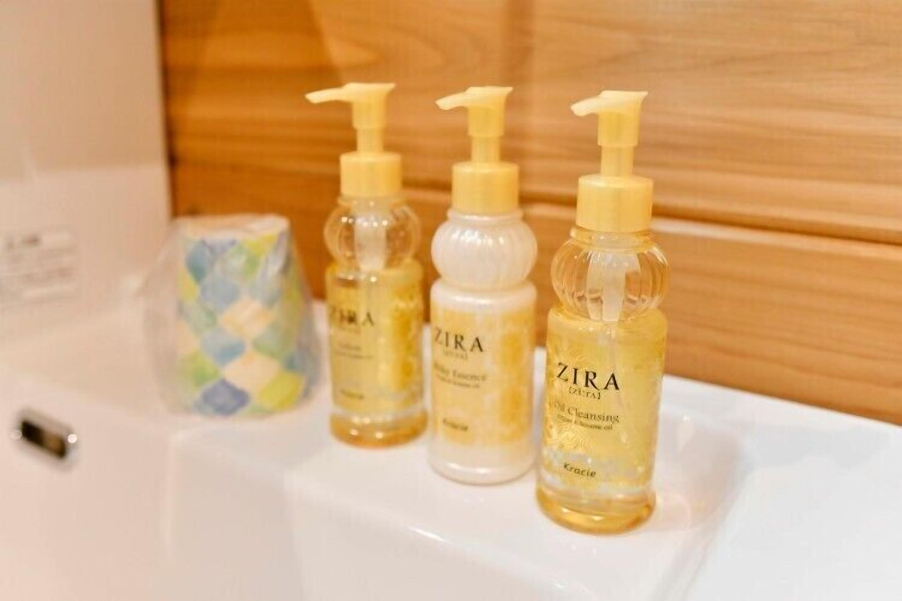 Trois flacons de lotion démaquillante à l’huile ZIRA sur un lavabo blanc.