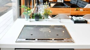 A modern kitchen with a built-in stove, a dishwasher, and a window overlooking a wooden interior. - Polar House Nishikaruizawa 1 (Karuizawa)