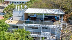 Un edificio de varios pisos con una terraza en la azotea, mobiliario exterior y zona de comedor.