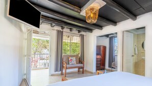 Habitación de hotel con cama, una silla de madera, televisor, lámpara en el techo y vistas al exterior.