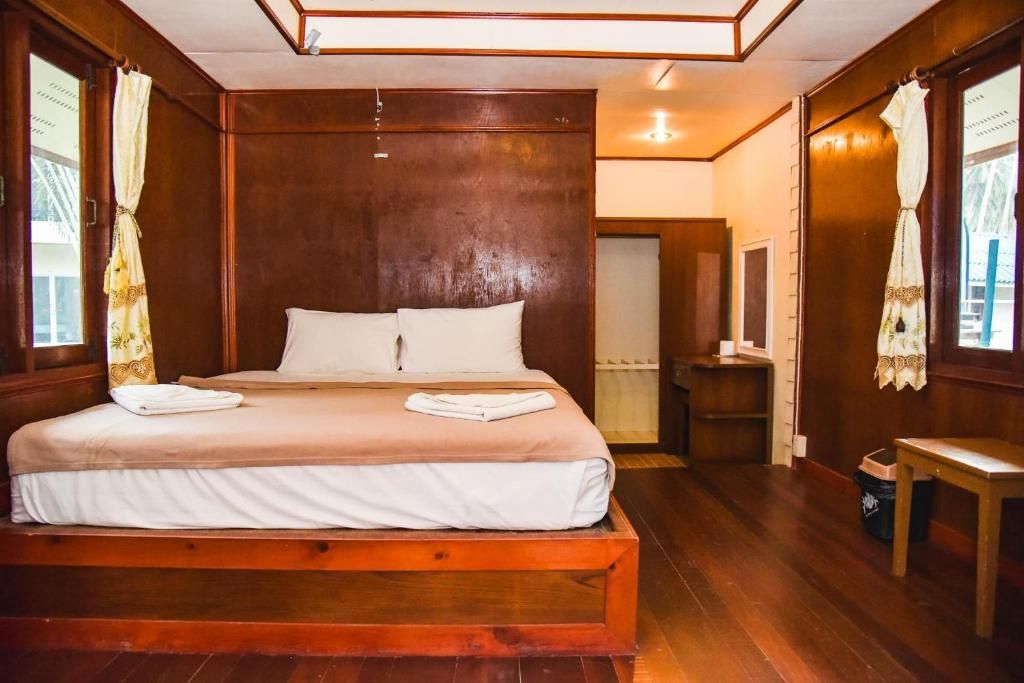 A wooden-framed bed with white bedding, a wooden nightstand, and a small table.