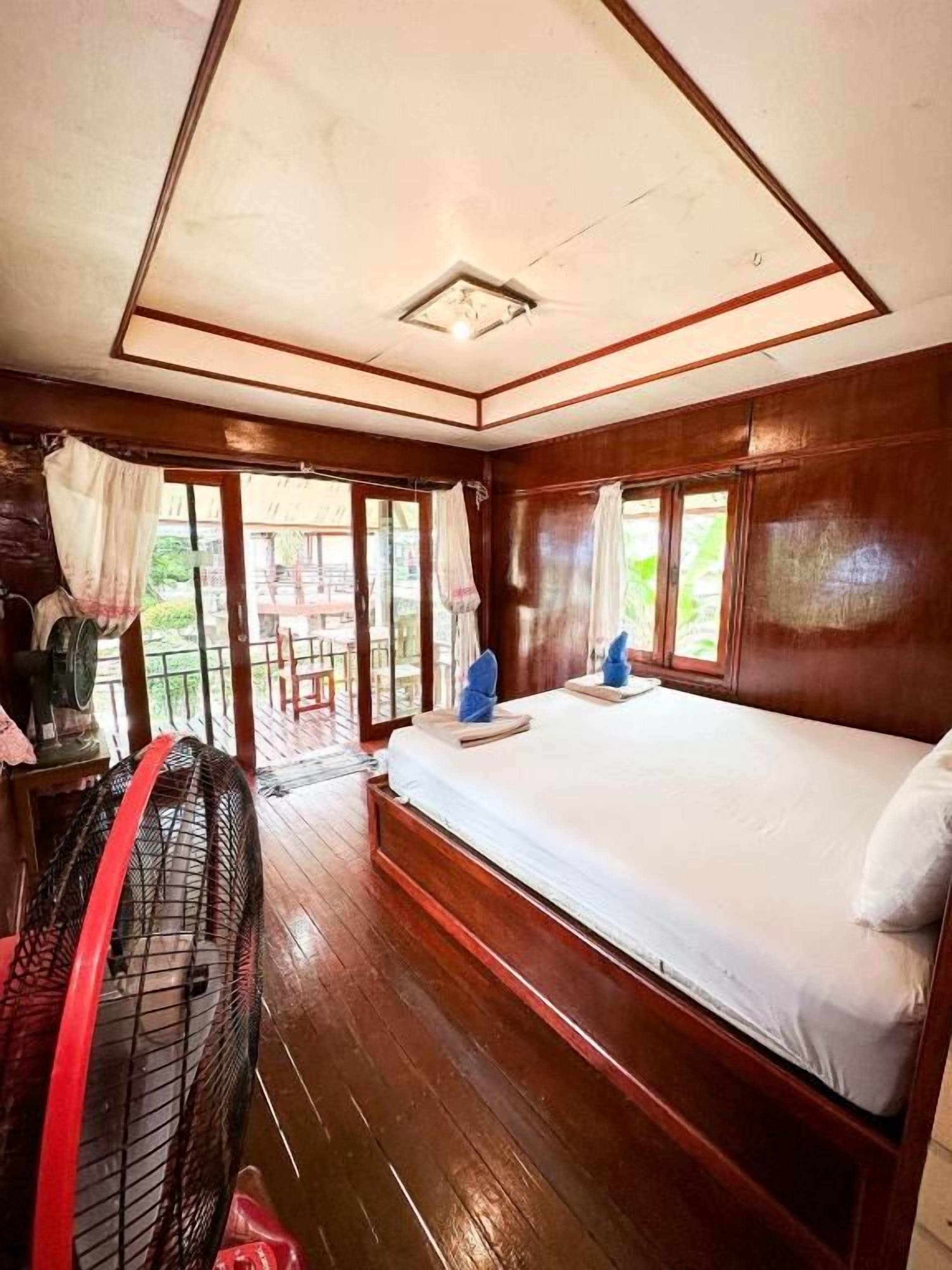 Une chambre avec un lit, un ventilateur et une vue sur l’extérieur.