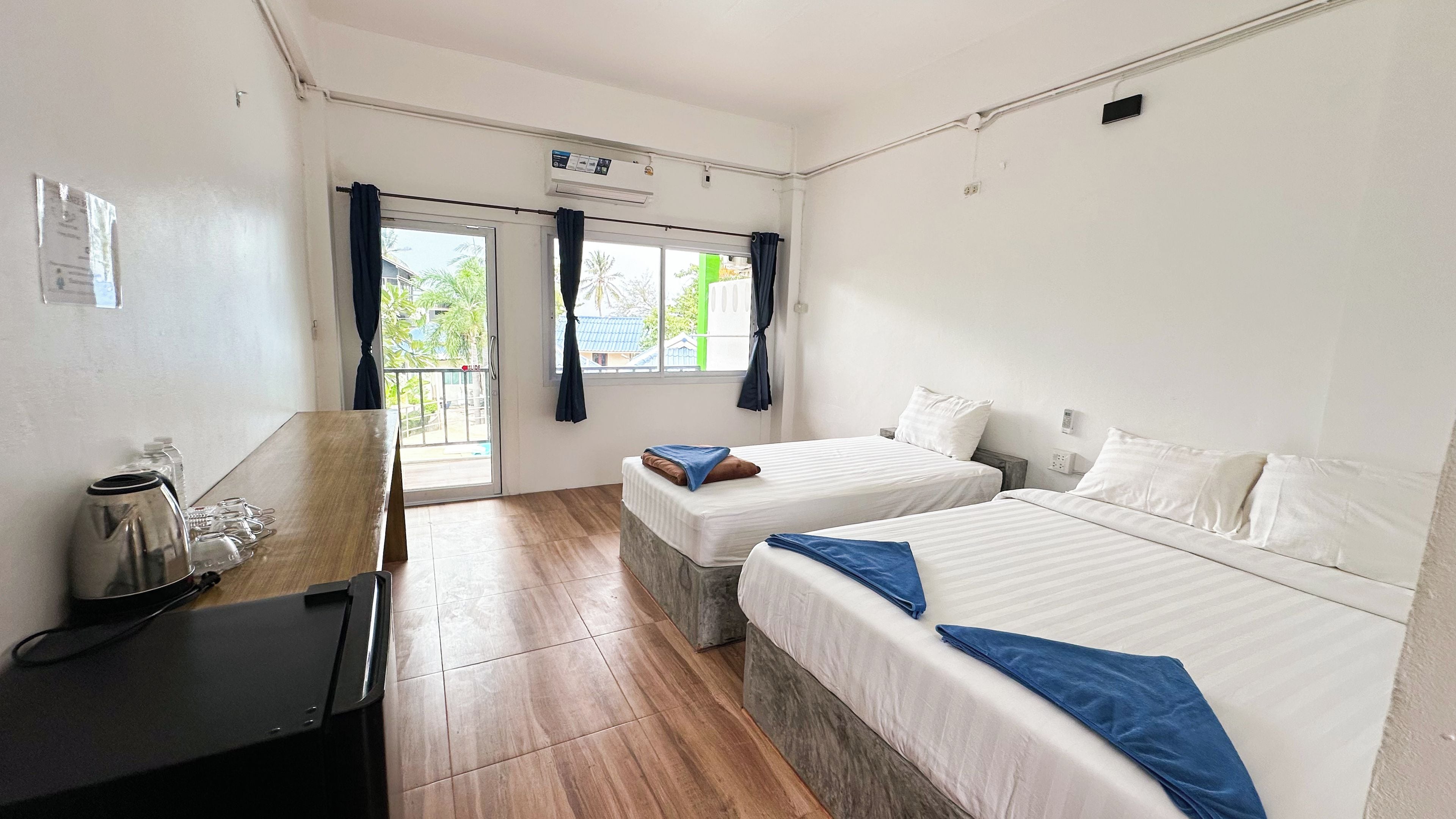 Habitación de hotel con dos camas, un escritorio y una ventana con cortinas.