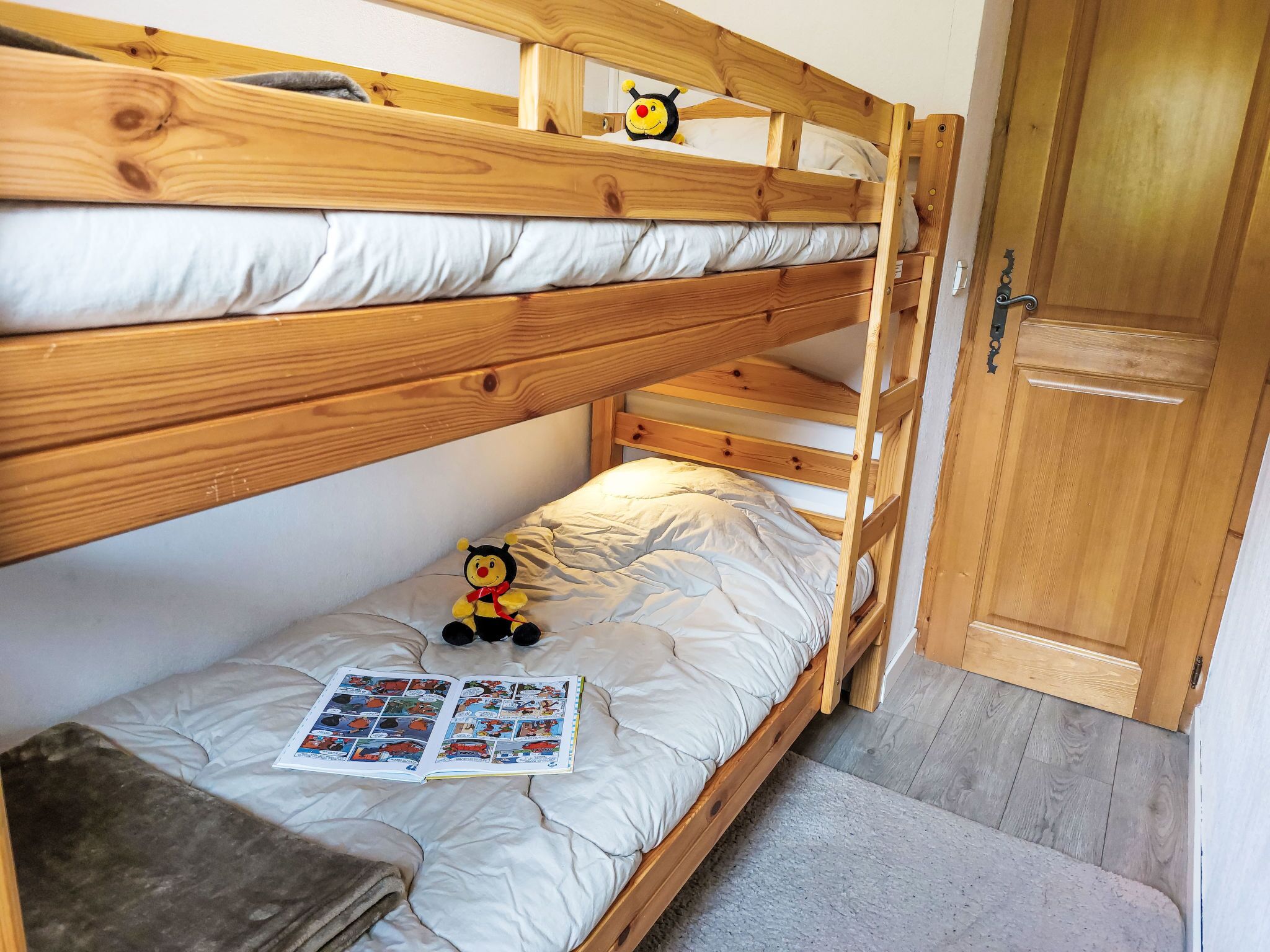 A bunk bed with a plush toy and a magazine on the lower bunk.