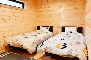 Une cabine équipée de deux lits en bois, chacun agrémenté d’une couverture à motifs et de coussins.