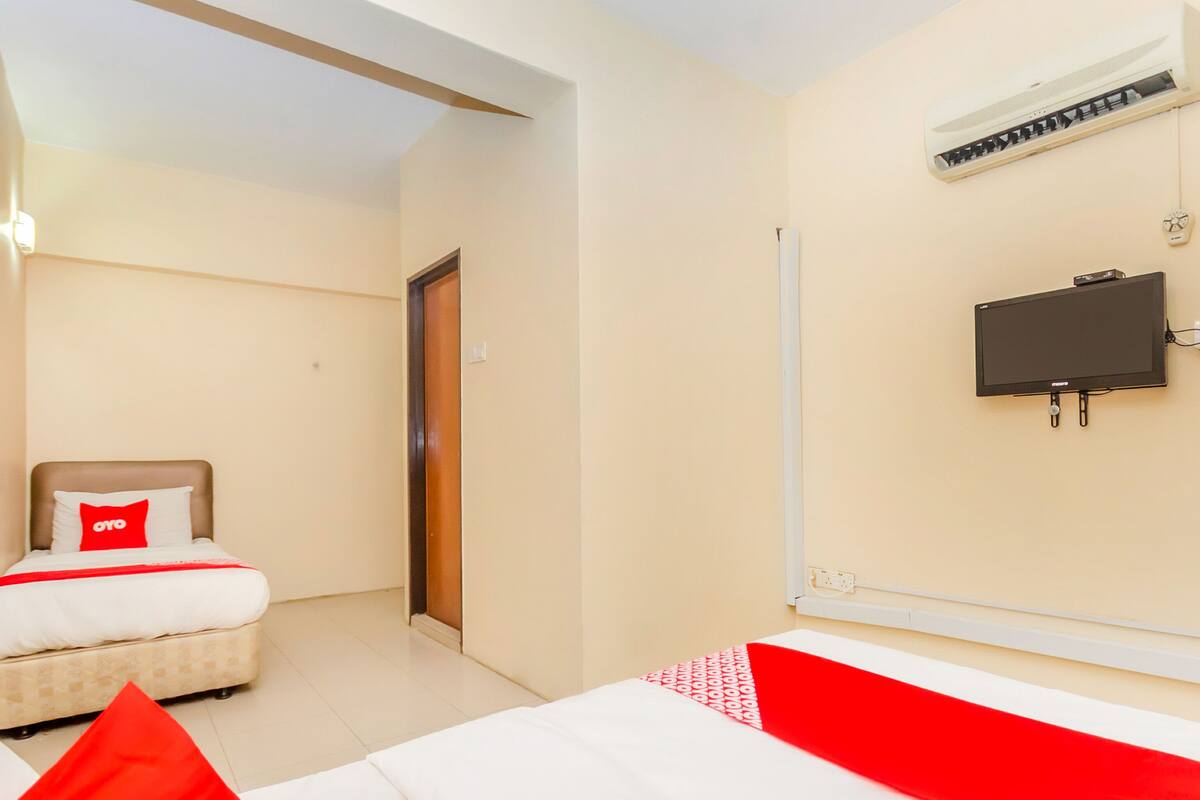 Een hotelkamer met een bed, een aan de muur bevestigde televisie en een airconditioner.
