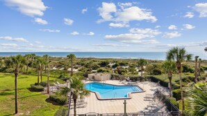 A pool area with lounge chairs and a view of the ocean. - Oceanfront | Pool View | Gorgeously Furnished 3rd Floor Amelia Surf and Racquet Condo (Fernandina Beach)