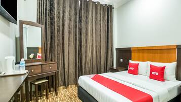 A hotel room with a bed, a desk, a mirror, and a window with curtains.