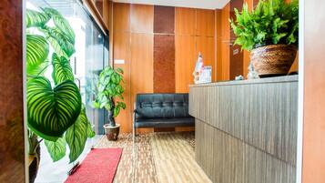 A reception area with a black leather sofa, a reception desk, and potted plants.