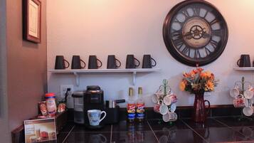 A kitchen counter with a coffee maker, mugs, and a clock.