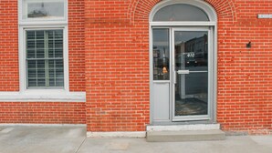 Un edificio de ladrillo rojo con un marco blanco en la ventana y una puerta de cristal donde se ve el número "60".