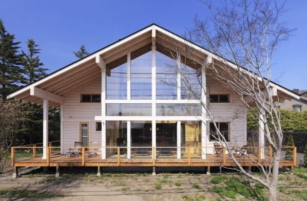 A modern house with a large glass window, a wooden deck, and a sloped roof. - Polar House Karuizawa 1 (Karuizawa)