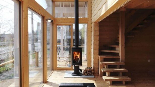 Un intérieur moderne avec une cheminée, un plancher en bois et de grandes fenêtres.