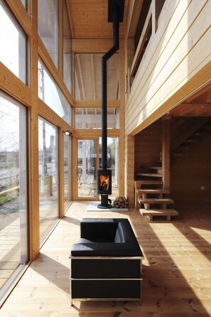 A modern interior with a fireplace, wooden flooring, and large windows. - Polar House Karuizawa 1 (Karuizawa)