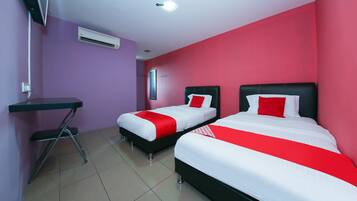 A hotel room with two beds, a desk, and an air conditioning unit.