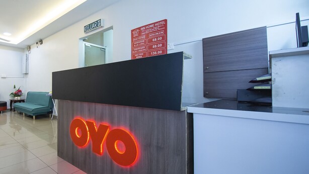 Un comptoir d'accueil d'hôtel avec une enseigne « OYO » bien visible, un espace d'accueil et un panneau indiquant les tarifs des chambres.