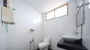 Une petite salle de bain moderne avec des carreaux blancs, des toilettes, un lavabo et une fenêtre.