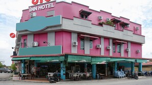 Un bâtiment rose avec une enseigne indiquant « OYO INN HOTEL ».