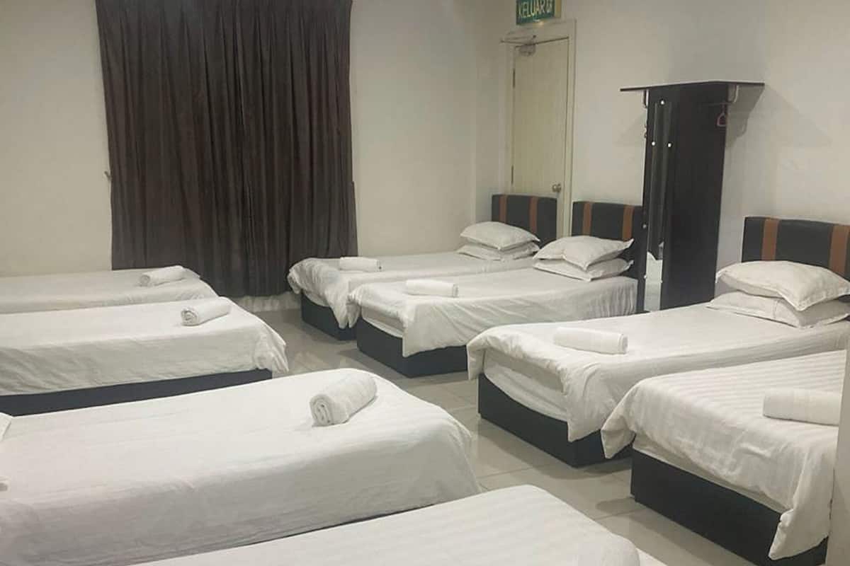 Ein Hotelzimmer mit sechs ordentlich bezogenen Betten, einem Kleiderschrank und einem Vorhang.