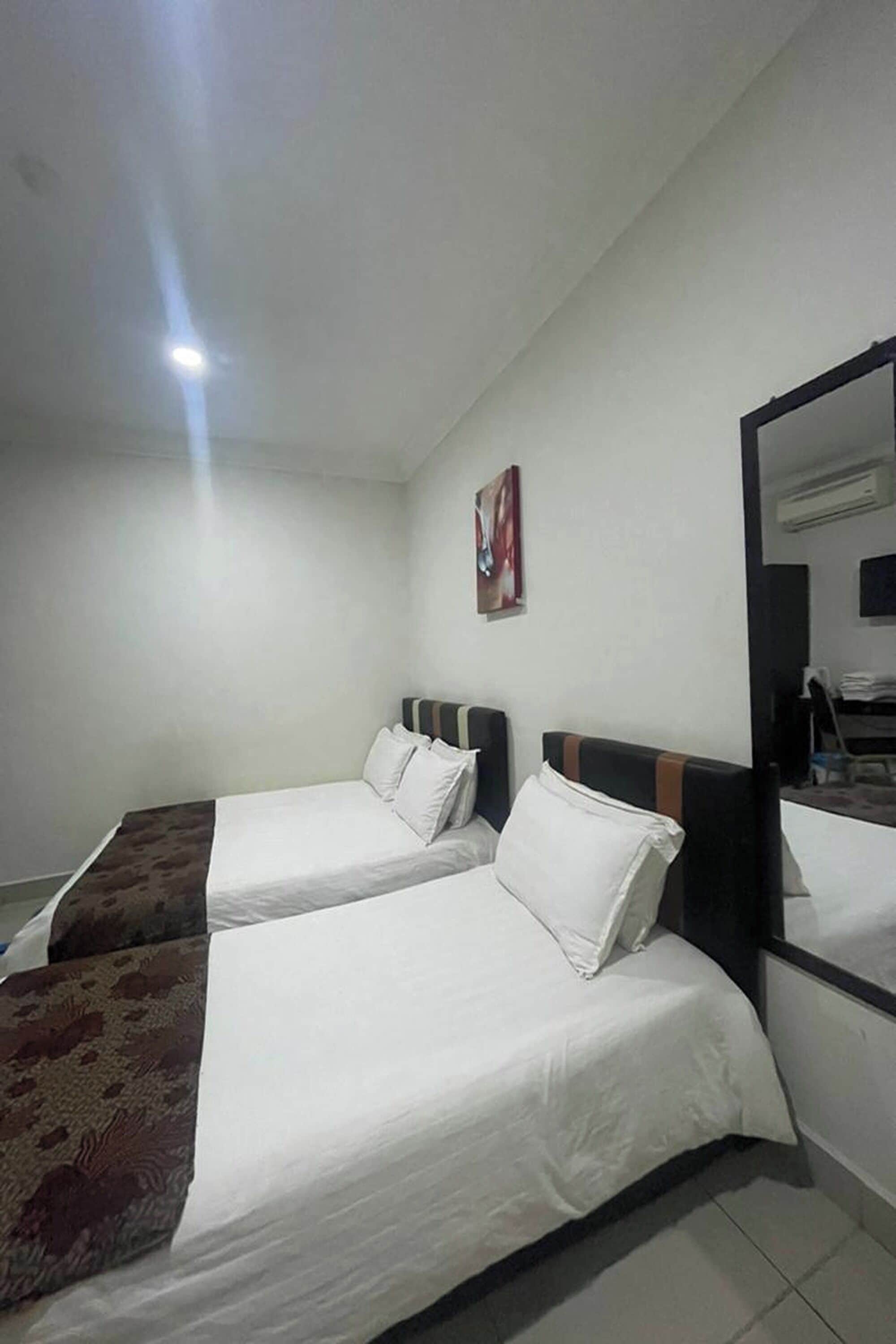 Habitación de hotel con dos camas individuales, un espejo grande, un televisor de pantalla plana y un cuadro en la pared.