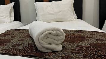Una cama bien hecha con una colcha estampada y una toalla enrollada encima.