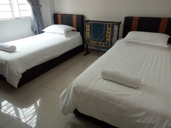Una habitación de hotel con dos camas individuales, una mesita de noche y un ventanal con cortinas.