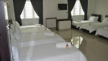 Habitación de hotel con tres camas, televisión y ventana con cortinas.