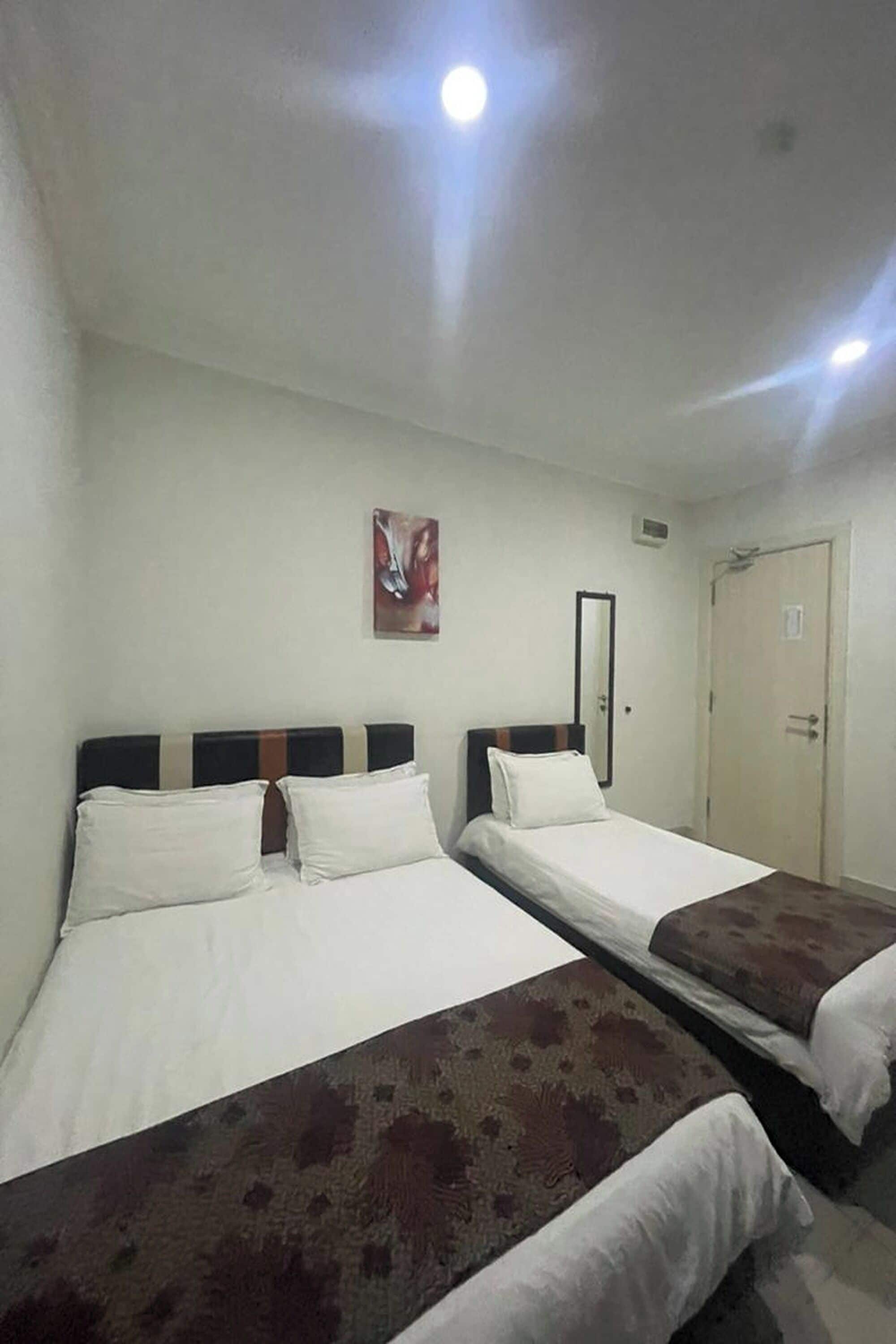 Een hotelkamer met twee bedden, een spiegel en een deur.
