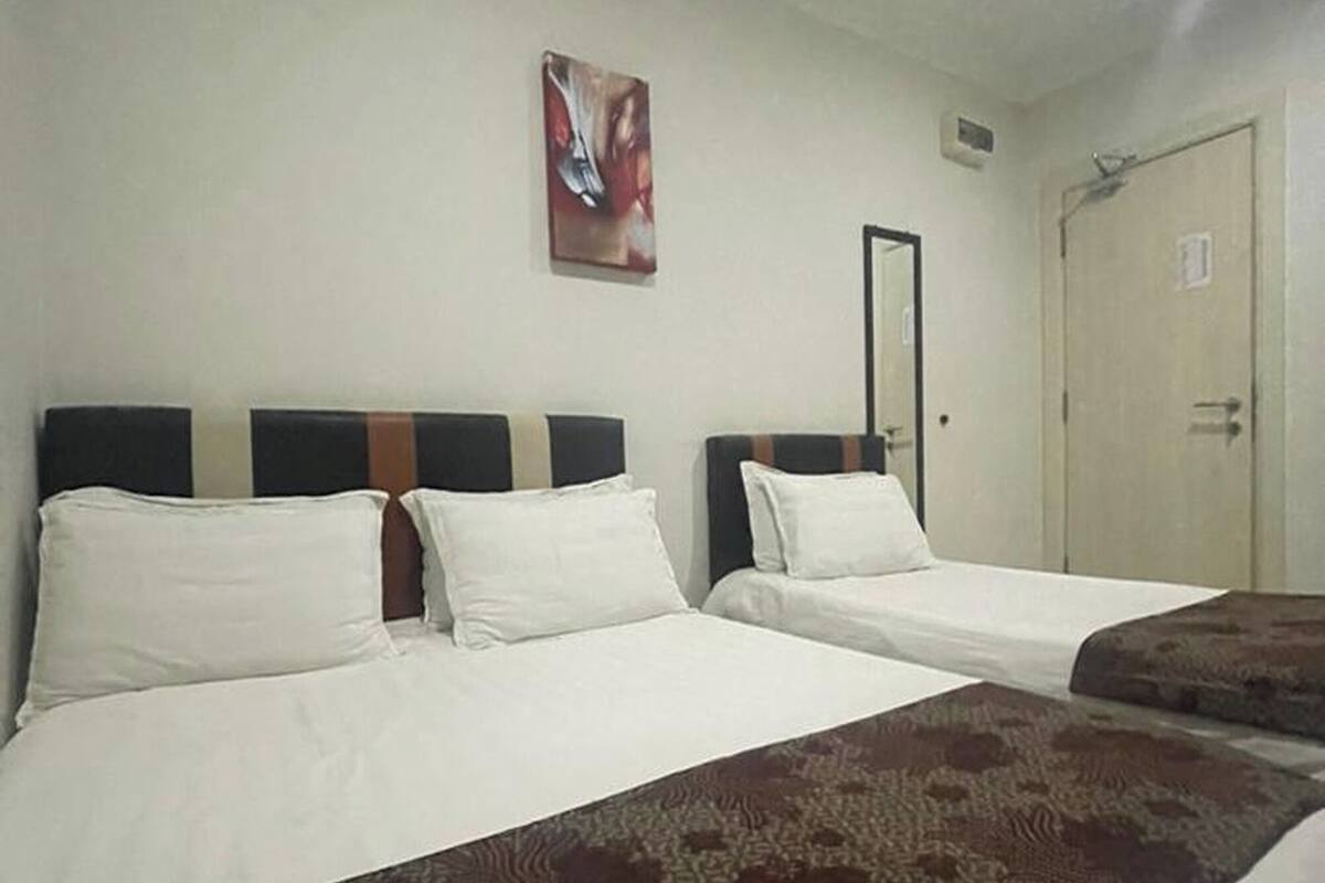 Ein Hotelzimmer mit zwei Betten, einem großen Fenster, einer Tür und einem an der Wand hängenden Kunstwerk.