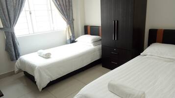 A hotel room with two single beds, a wardrobe, and a window with curtains.