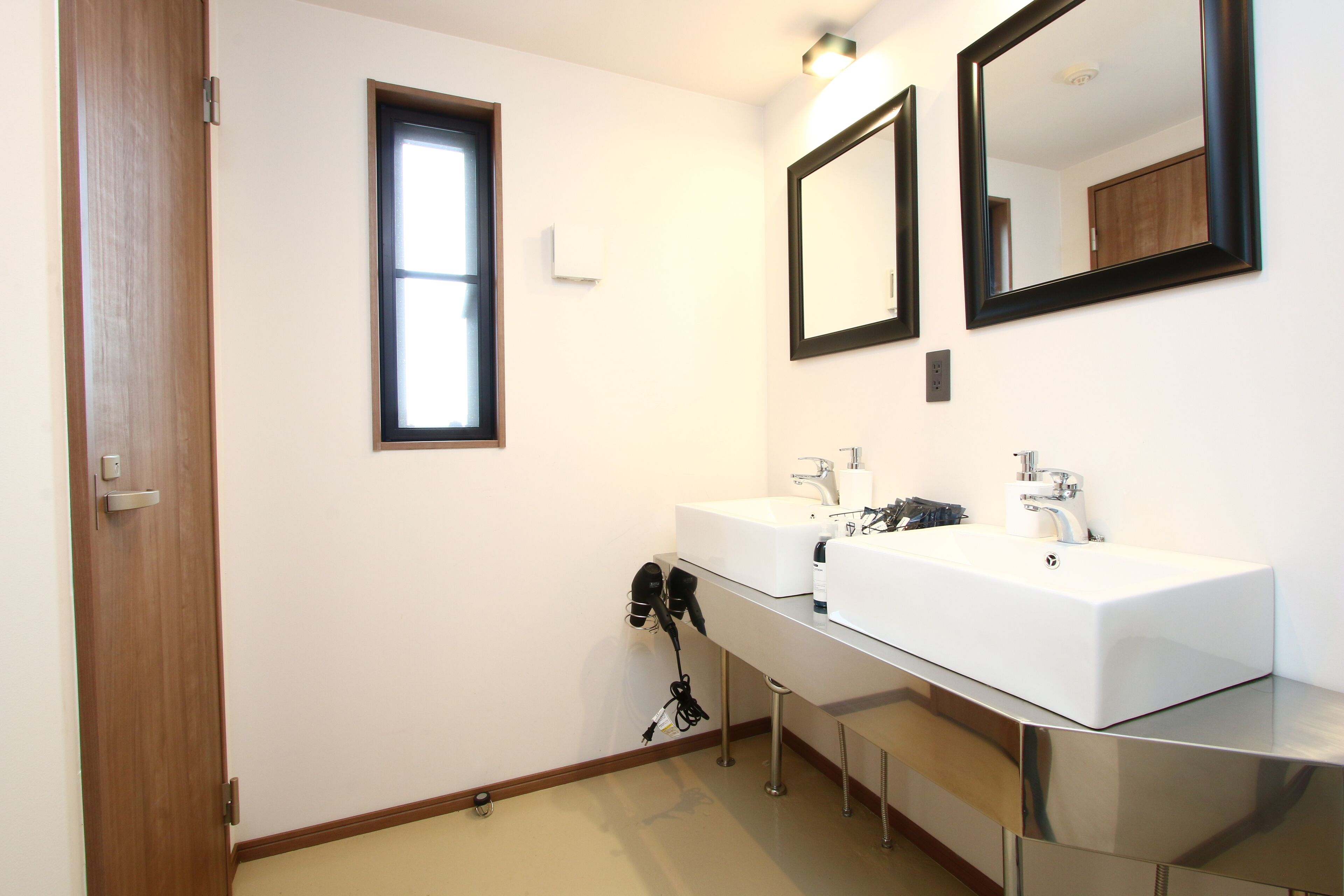 Un baño moderno con dos lavamanos, una ventana y un espejo.