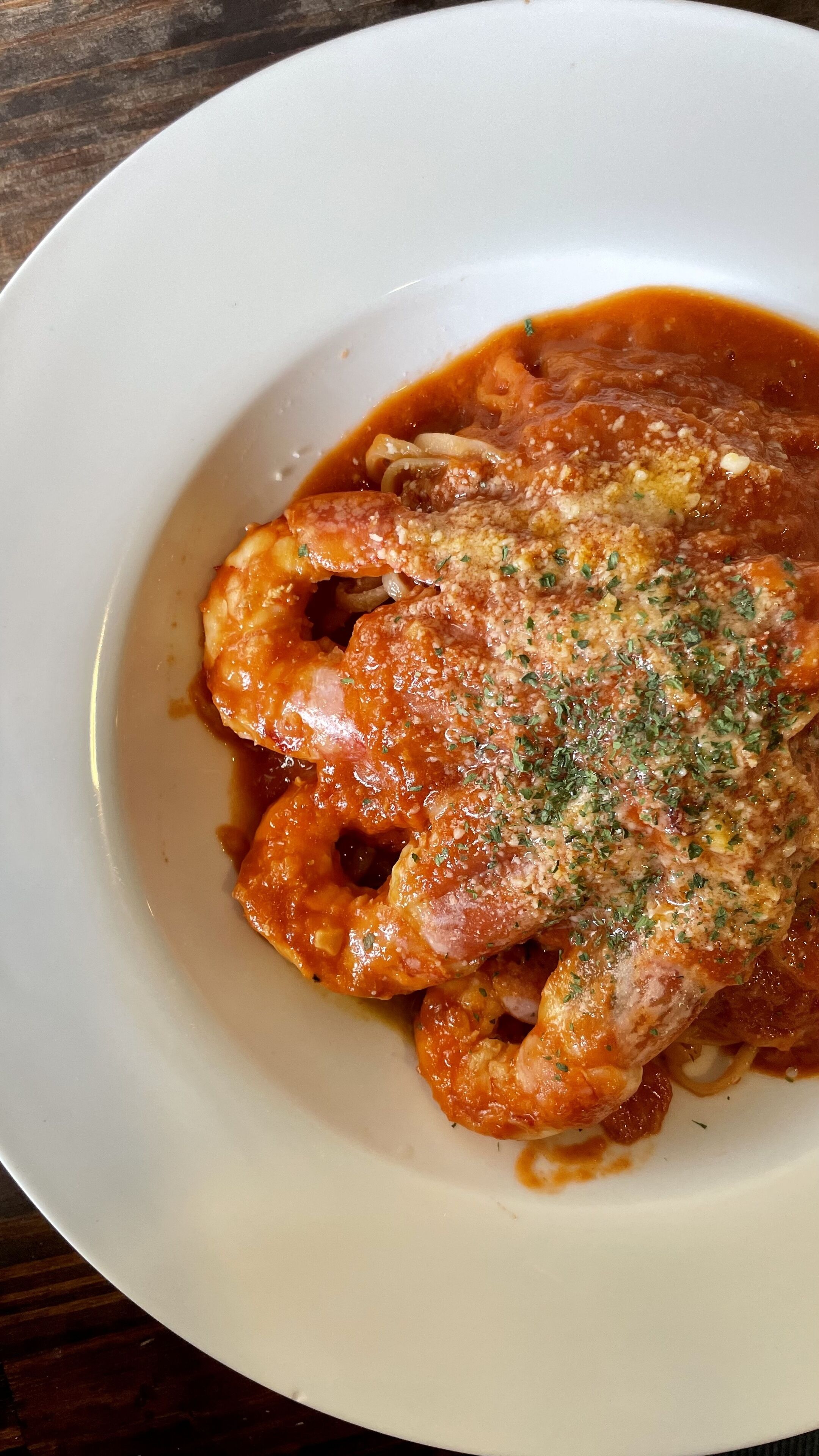 A plate of pasta with a tomato-based sauce, garnished with herbs.