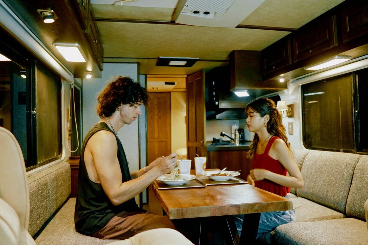 A compact RV interior with a kitchenette, a dining table, and seating area.