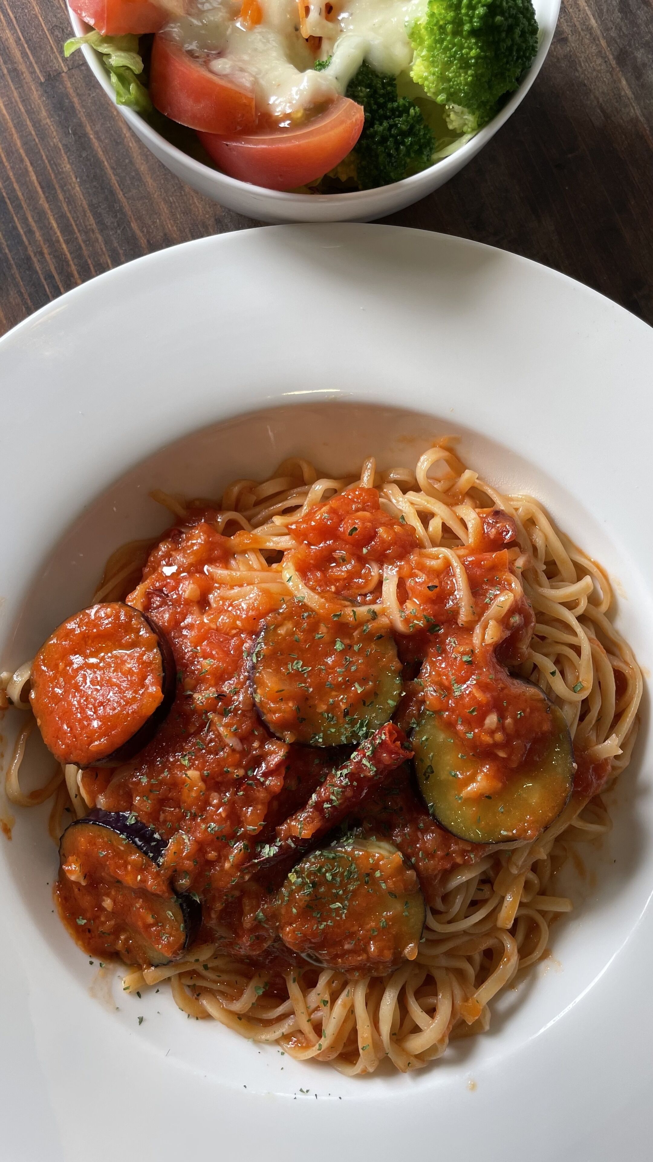 A plate of spaghetti with tomato sauce and vegetables.