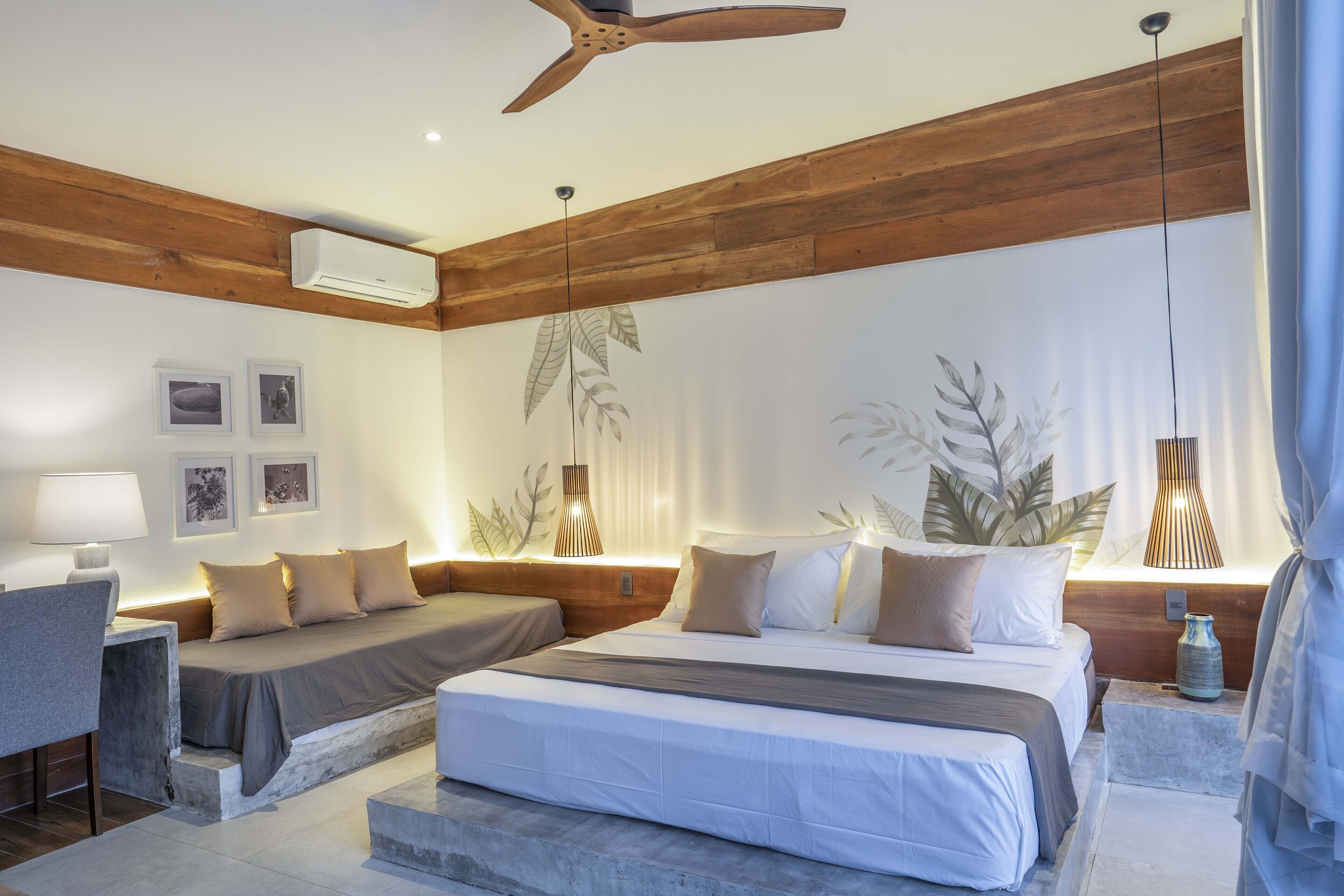 Une chambre d’hôtel moderne, dotée d’un grand lit, d’un bureau et d’un ventilateur de plafond.