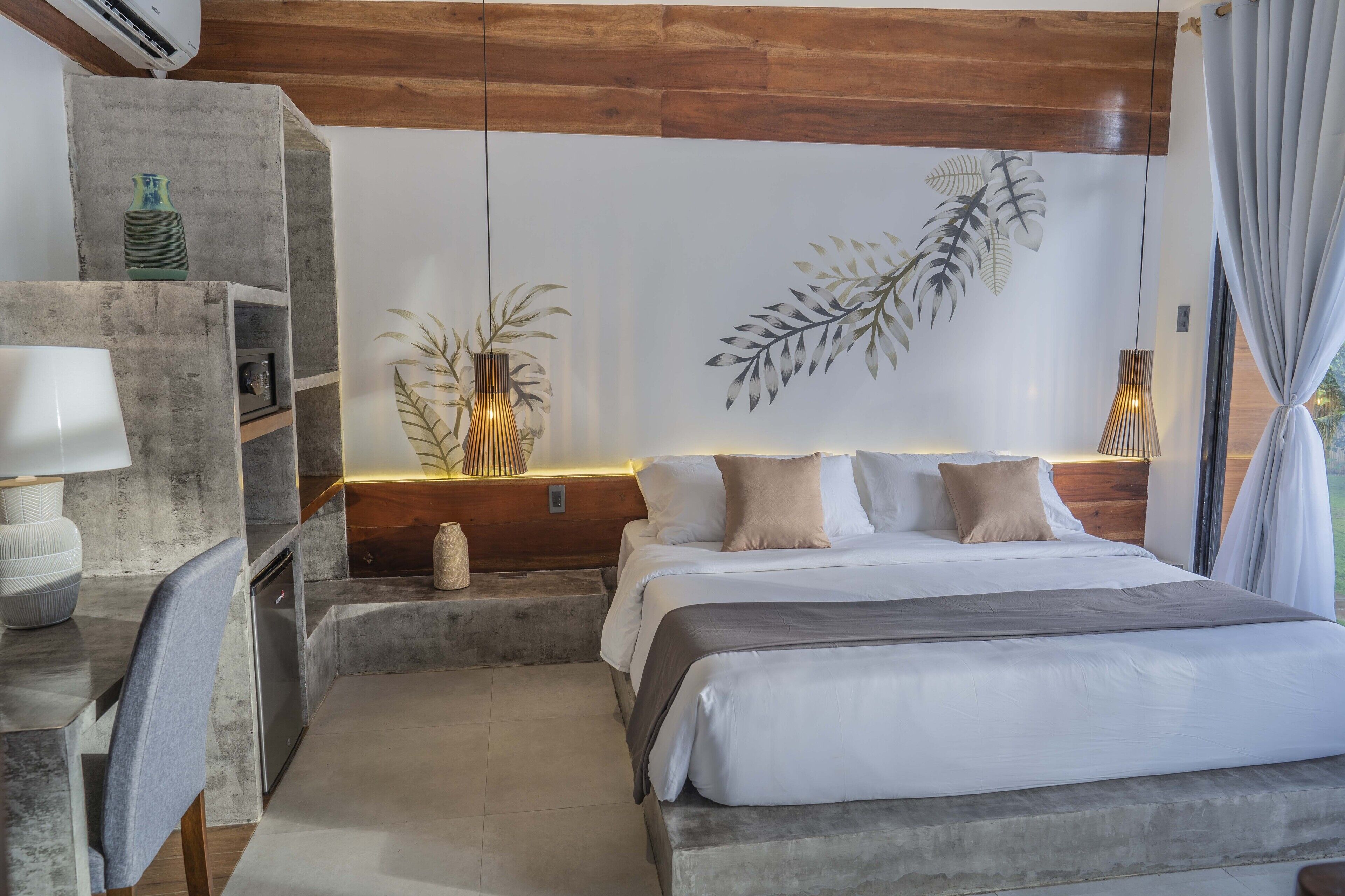 A bedroom with a bed, bedside tables, a desk, and a chair.