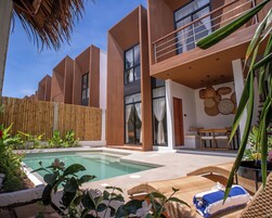 Una casa moderna con piscina, terraza de madera y mobiliario exterior.