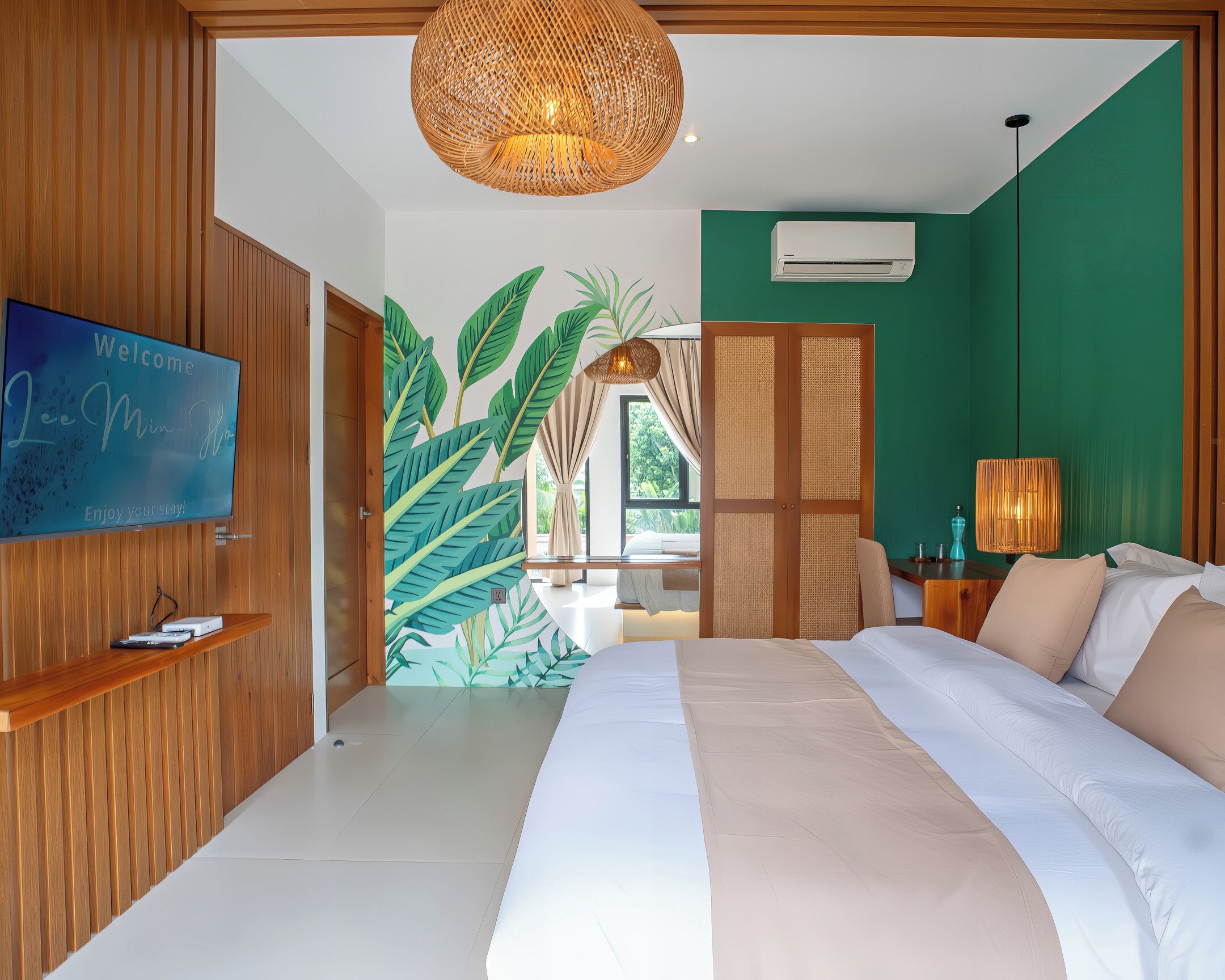 Ein modernes Schlafzimmer mit einem großen Bett, einem Fernseher, einer Wand-Klimaanlage und einem Wandbild mit tropischem Motiv.