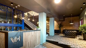 Zona de recepción con diseño moderno, que incluye un mostrador de recepción, una escalera y un área de descanso.