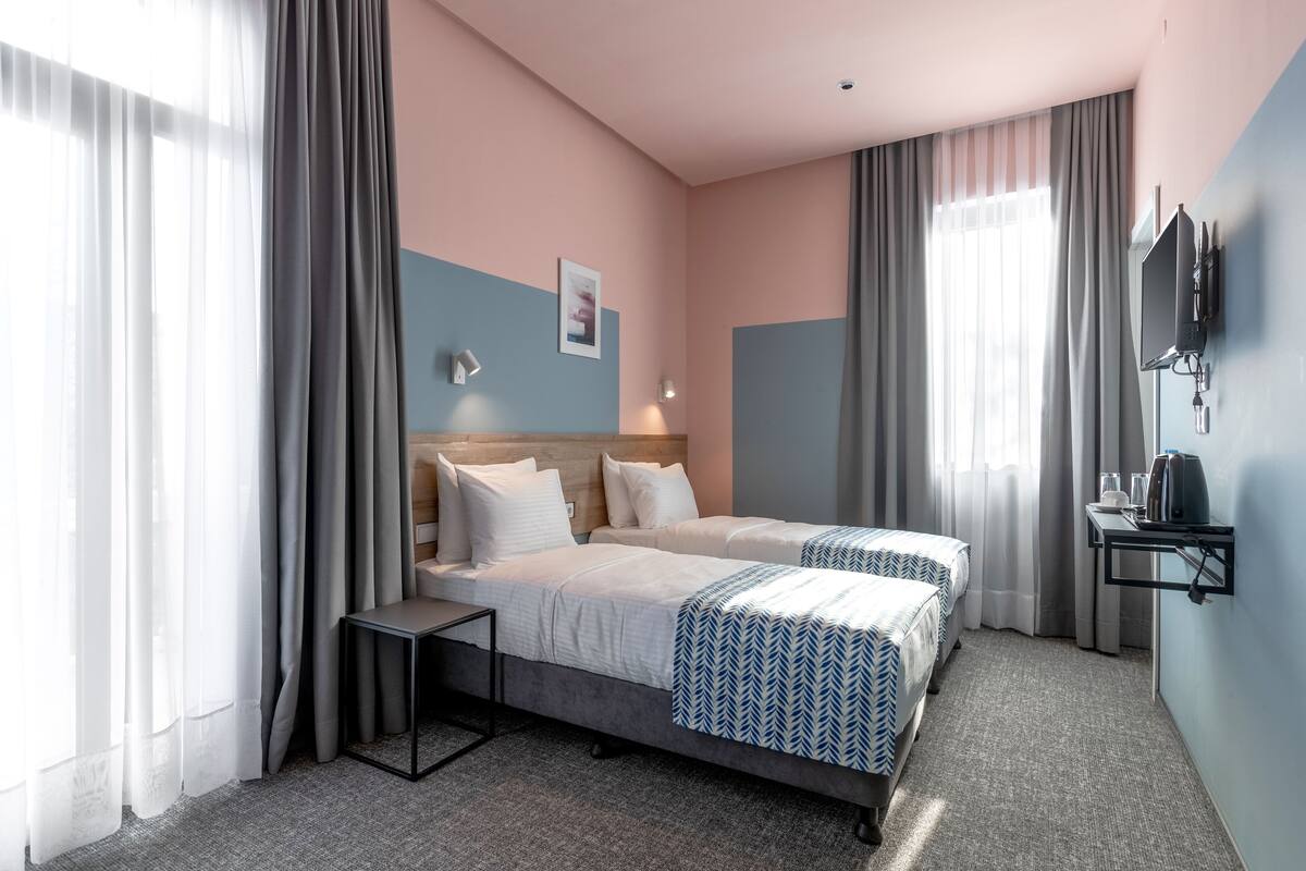 A hotel room with two beds, a small table, a TV, and a coffee machine.