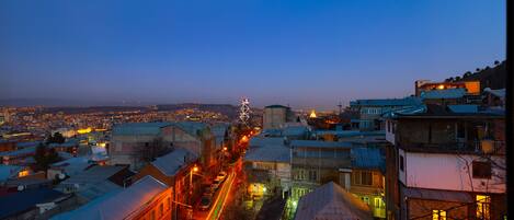A cityscape at dusk with illuminated buildings and a busy street.