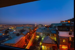 A cityscape at dusk with illuminated buildings and a busy street.