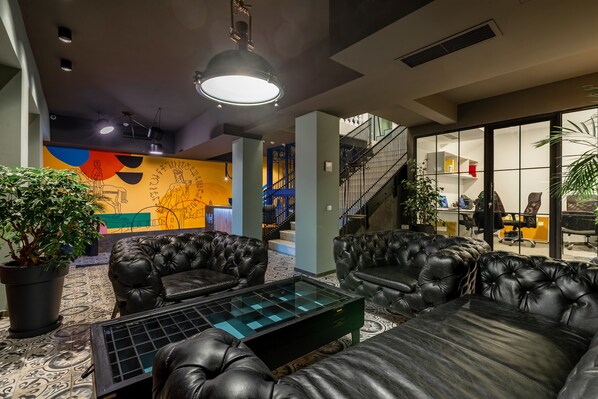 Un área de descanso moderna con sofás de cuero, una mesa de centro de vidrio y un mural colorido.