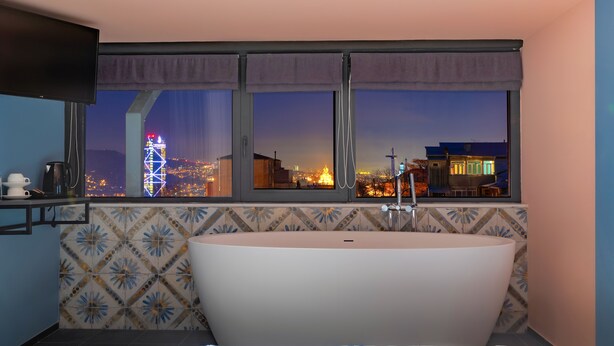 Un baño moderno con una bañera independiente, un ventanal con vista a la ciudad y un salpicadero de azulejos.
