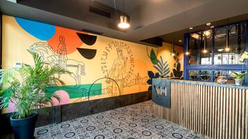 Un moderno vestíbulo de hotel con un mural colorido, un mostrador de recepción y pisos con diseños.