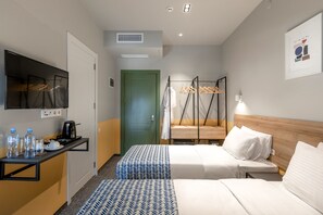Habitación de hotel con dos camas, una kitchenette pequeña, un televisor y un perchero.