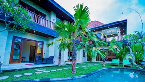 Una casa moderna con piscina, mobiliario de exterior y exuberante vegetación.