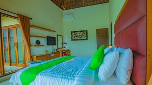 Habitación de hotel con cama, escritorio, silla, televisor y ventana con cortinas.