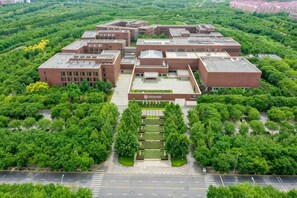 A large institutional building with multiple brick structures, surrounded by dense greenery. - NCEC Jinyuan Hotel (TIANJIN)