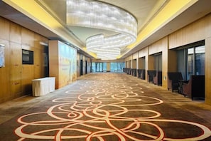 A hotel corridor with a patterned carpet, wooden paneling, and a modern chandelier. - NCEC Jinyuan Hotel (TIANJIN)